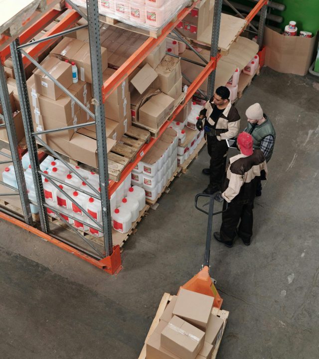Three warehouse workers discussing inventory organization details.